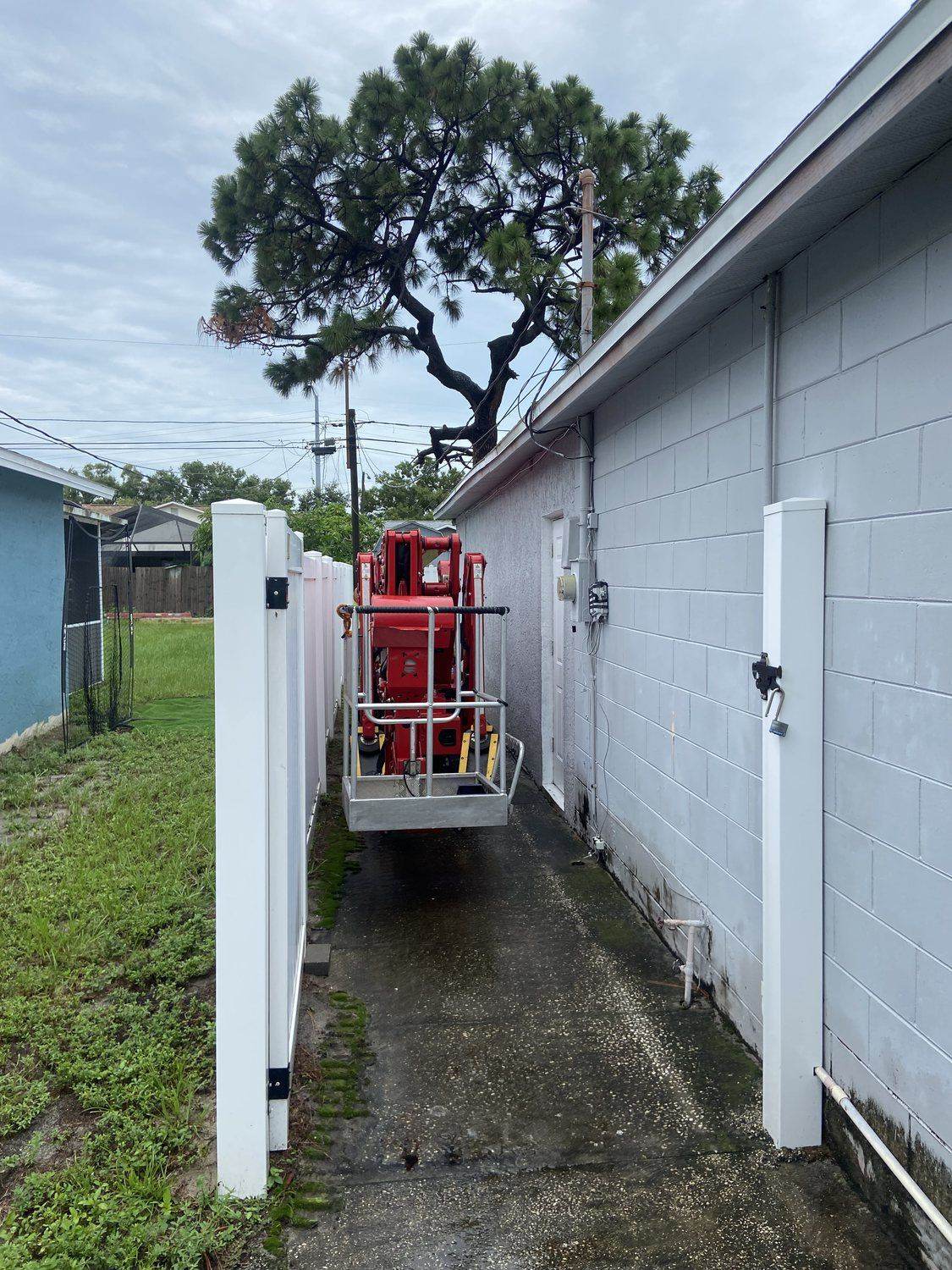 Triangle Tree Service lift fitting through a narrow side-yard gate in St. Petersburg, the same tight access our stump grinder works in