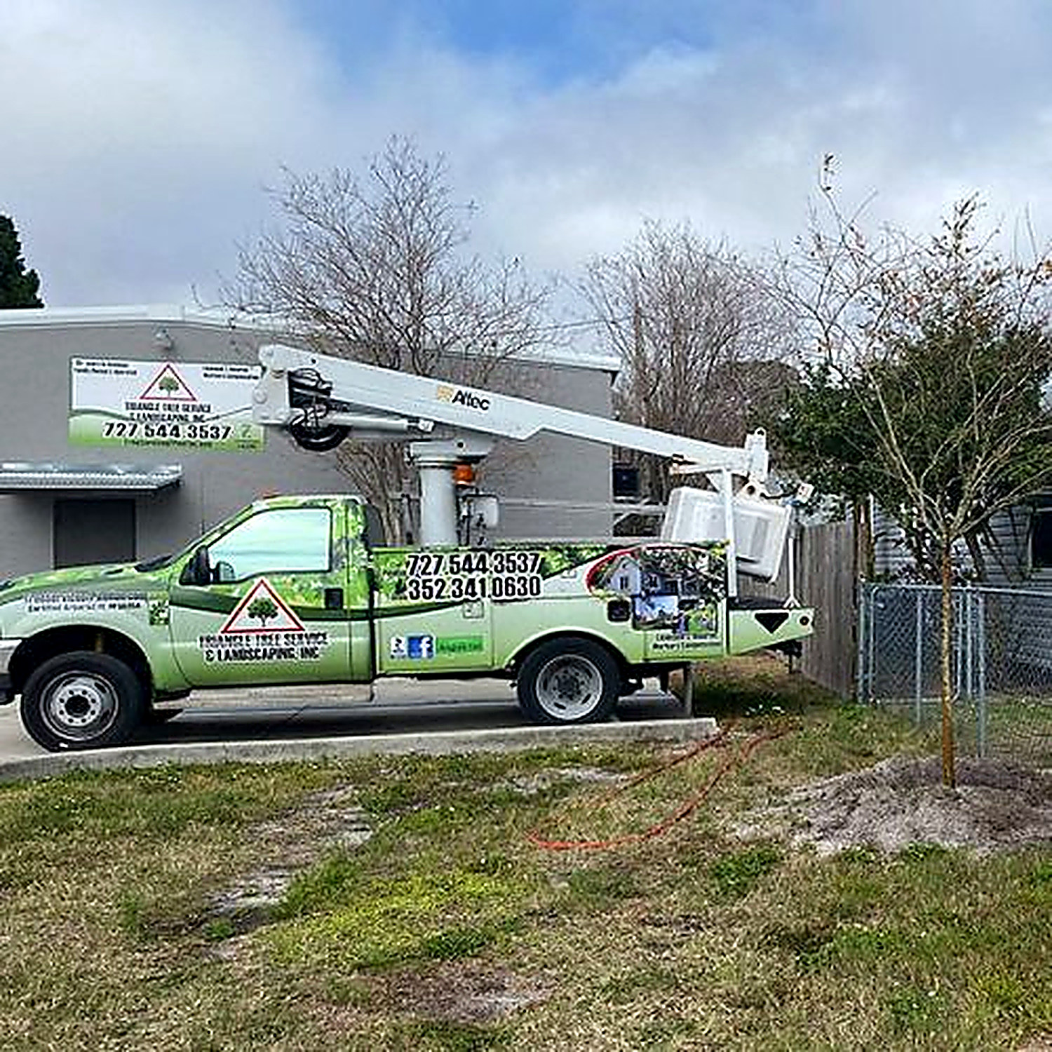 The branded Triangle Tree Service and Landscaping bucket truck parked at a job site